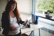 Schwangere Geschäftsfrau liest im Büro Papierdokumente — Stockfoto