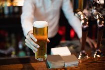 Бармен, яка виступає з келихом пива на зустрічну в бар — стокове фото