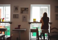 Visão traseira da mulher sentada na janela no interior do restaurante — Fotografia de Stock