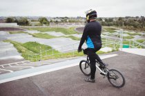 Ciclista in piedi con BMX bike alla rampa di partenza in skatepark — Foto stock
