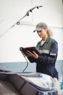 Meccanico femminile che utilizza un dispositivo diagnostico elettronico nel garage di riparazione — Foto stock