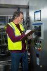 Trabajador manual analizando maquinaria en fábrica - foto de stock