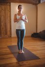 Mid adult woman practicing yoga in fitness studio interior — Stock Photo