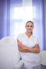 Портрет улыбающегося стоматолога, стоящего со скрещенными руками в клинике — стоковое фото