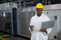 Travailleur masculin sérieux utilisant un ordinateur portable dans l'industrie manufacturière — Photo de stock