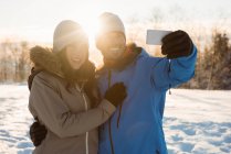 Couple heureux prenant un selfie sur un paysage enneigé — Photo de stock