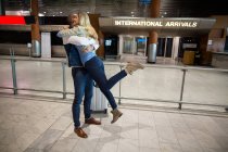 Couple joyeux s'embrassant dans la salle d'attente au terminal de l'aéroport — Photo de stock