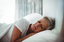 Пожилая женщина отдыхала на кровати в спальне дома — стоковое фото