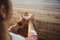 Primo piano della donna che tiene una tazza di caffè nel caffè — Foto stock