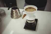 Imbuto filtro caffè e pentola di acqua calda sul tavolo in caffetteria — Foto stock