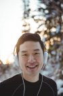 Retrato del hombre escuchando música en auriculares durante el invierno - foto de stock
