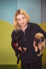 Portrait of woman carrying black and brown pug dogs at dog care center — Stock Photo