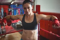 Fiducioso pugile donna appoggiato sul ring di boxe in palestra — Foto stock
