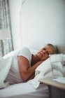 Senior woman resting on bed in bedroom at home — Stock Photo