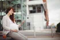 Femme d'affaires enceinte tenant une tablette numérique dans des locaux de bureau — Photo de stock