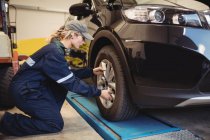 Female mechanic examining a car wheel in repair garage — Stock Photo
