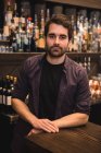 Ritratto di barista sicuro in piedi al bancone del bar — Foto stock