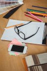 Telefone móvel com prancheta, óculos, lápis e notas pegajosas na mesa no escritório — Fotografia de Stock