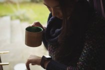 Mulher olhando para relógio inteligente enquanto toma café em casa — Fotografia de Stock