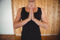 Partie médiane de la femme effectuant du yoga dans un studio de fitness — Photo de stock