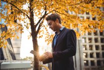 Geschäftsmann im Herbst mit digitalem Tablet auf der Straße — Stockfoto