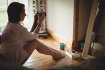 Donna che scatta foto sulla macchina fotografica digitale a casa — Foto stock