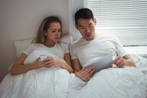 Paar nutzt digitales Tablet zu Hause im Schlafzimmer — Stockfoto