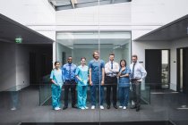 Portrait of smiling doctors standing together in corridor at hospital — Stock Photo