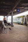 Vista lateral da empresária esperando no banco para o trem viajar — Fotografia de Stock