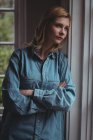 Thoughtful woman leaning on wall at home — Stock Photo