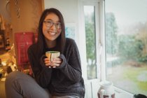 Портрет женщины, держащей чашку кофе на кухне дома — стоковое фото