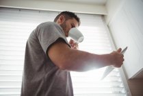 Людина використовує цифровий планшет, маючи каву на кухні вдома — стокове фото