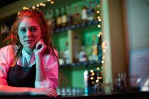 Retrato de uma barman feminina apoiada no balcão do bar — Fotografia de Stock