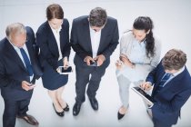 Vista aérea de gente de negocios usando teléfono móvil y tableta digital en la oficina - foto de stock