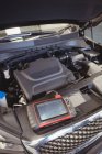 Auto con cofano aperto e dispositivo diagnostico in garage di riparazione — Foto stock