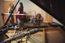 Крупним планом мікрофон у студії звукозапису з музикантами у фоновому режимі — стокове фото