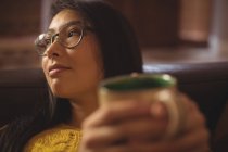 Frau sitzt und hält eine Kaffeetasse zu Hause — Stockfoto