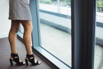 Низька секція бізнес-леді, що стоїть біля вікна в офісі — стокове фото
