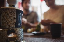 Крупный план зажженной свечи в керамическом горшке в ресторане — стоковое фото