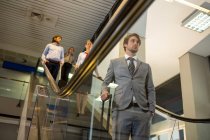 Passengers with luggage standing on escalator in airport — Stock Photo