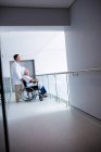 Médico de pé com paciente sênior do sexo masculino em uma cadeira de rodas no hospital — Fotografia de Stock