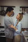Casal abraçando uns aos outros na cozinha em casa — Fotografia de Stock