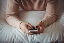 Frau benutzt Handy im Schlafzimmer zu Hause — Stockfoto