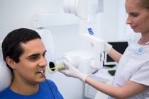 Dentista levando os dentes dos pacientes do sexo masculino raio-x na clínica — Fotografia de Stock