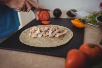 Mani di uomo affettare pomodoro fresco sul tagliere in cucina a casa — Foto stock