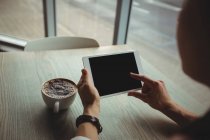 Жінка використовує цифровий планшет, маючи чашку кави в кафе — стокове фото