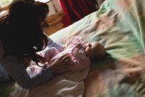 Мать играет с младенцем в спальне дома — стоковое фото