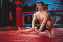 Sportsman doing stretching exercise in fitness studio — Stock Photo