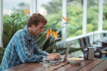 Man sitting at table and using laptop at home — Stock Photo
