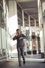 Бизнесмен разговаривает по мобильному телефону во время проверки времени возле офисного здания — стоковое фото